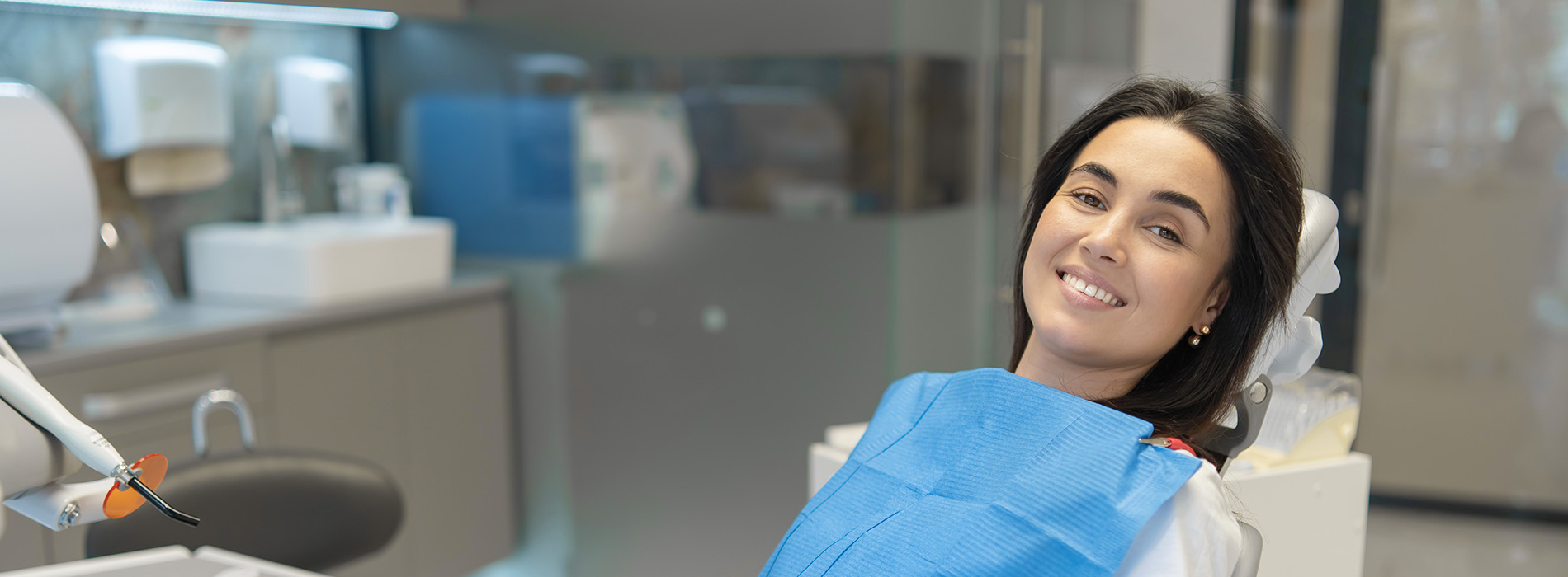 A woman sitting in a dental chair with her eyes closed, receiving dental care.