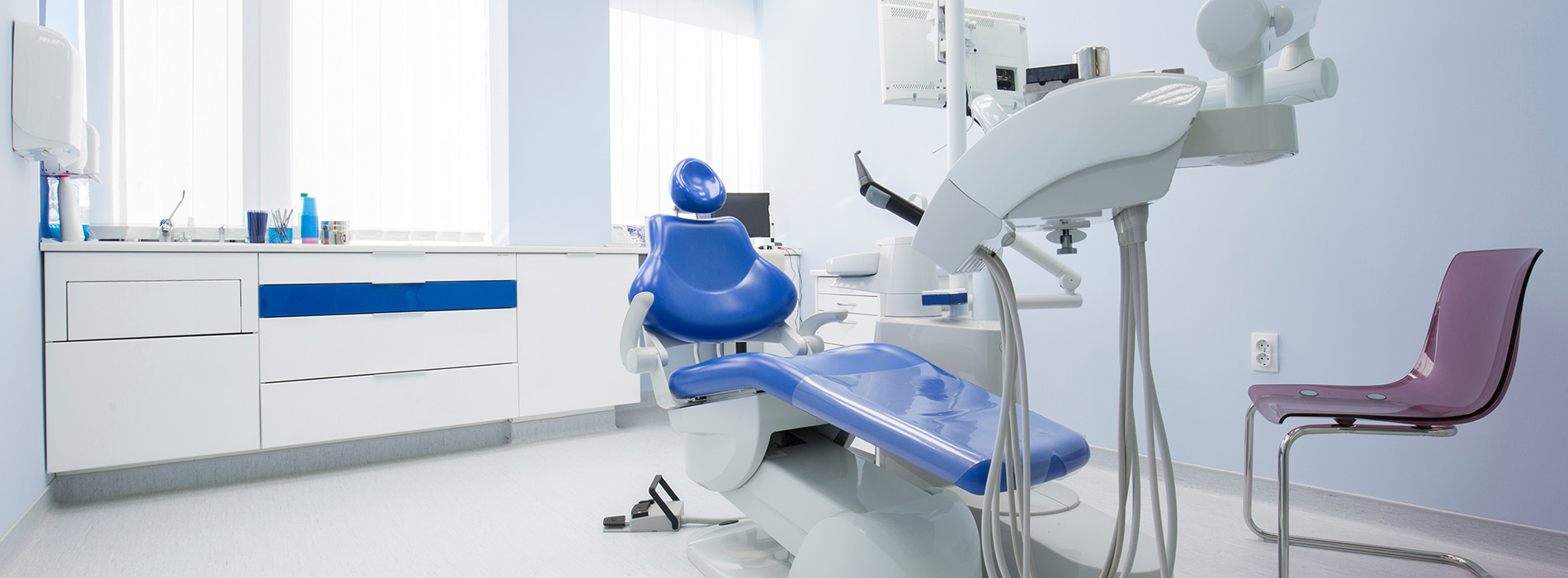 An image depicts a modern dental office interior with various pieces of equipment and a chair, showcasing a professional environment for dental care.