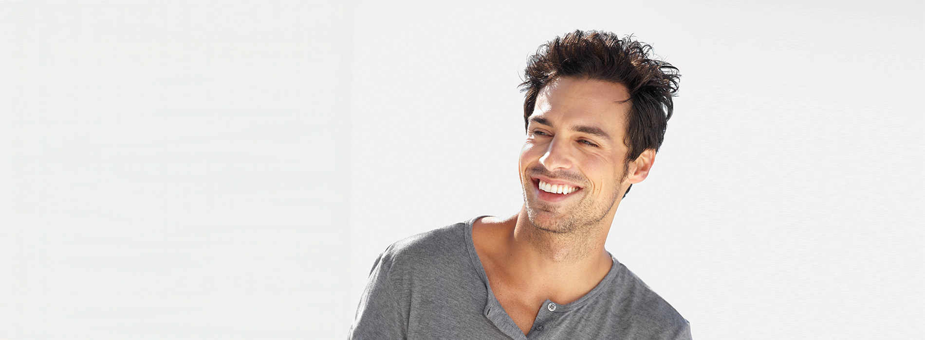 The image shows a smiling man with short hair, wearing a dark shirt, against a white background.