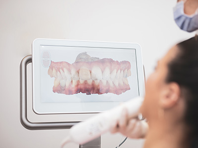 A person interacting with a digital display showing an image of teeth, likely at a dental office or similar setting.