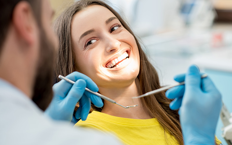 A woman receiving dental care with a smiling expression while a dentist works on her teeth.