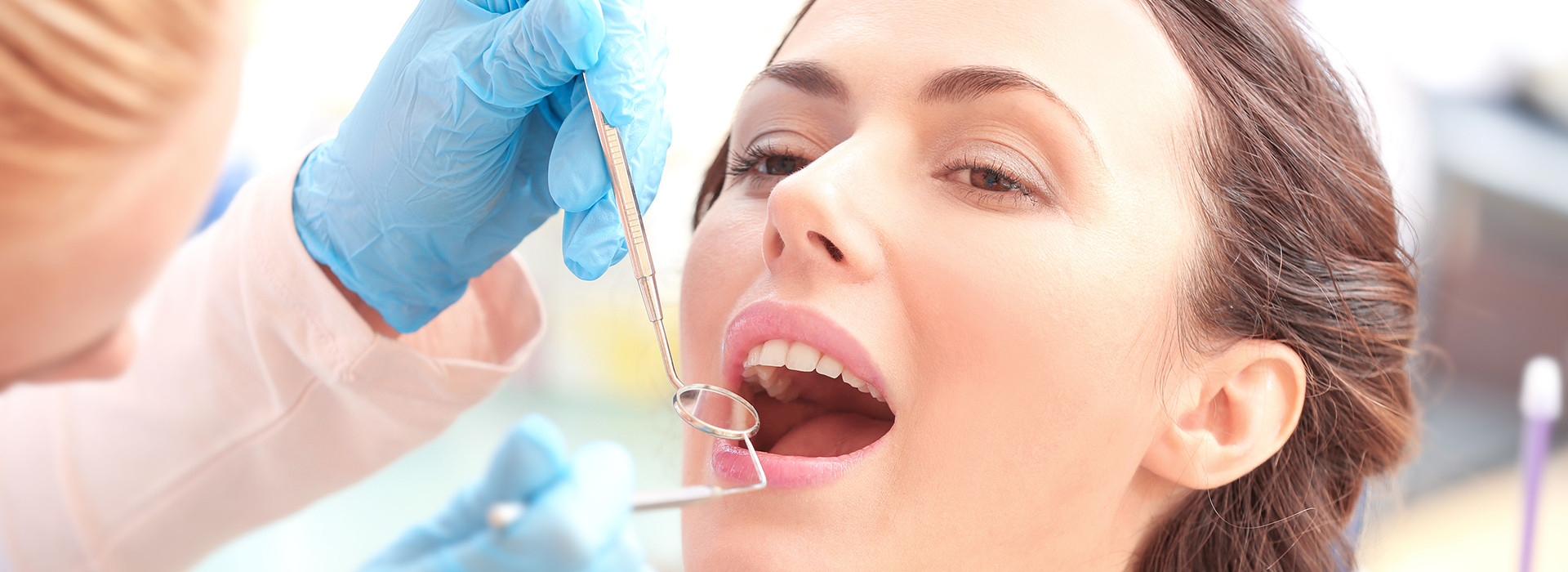 A dental hygienist performing a teeth cleaning procedure on a patient s mouth using a dental drill.