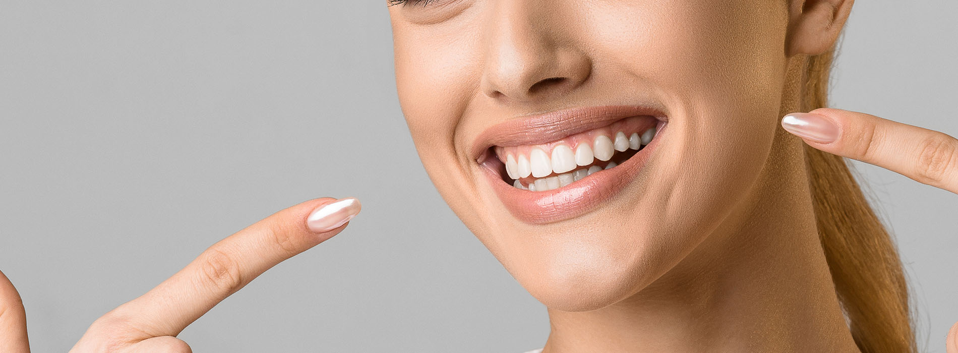 A smiling woman with a manicure gesture her fingers at the camera.