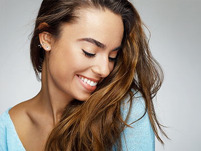A smiling woman with long hair, wearing a light blue top.